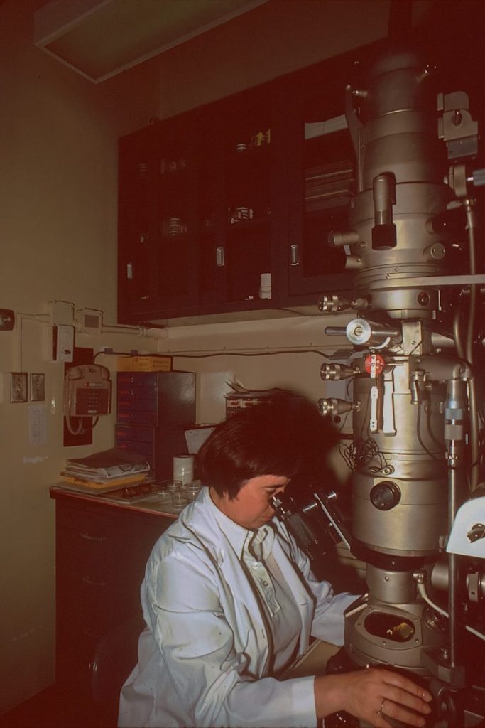 a woman looking through a microscope in a lab