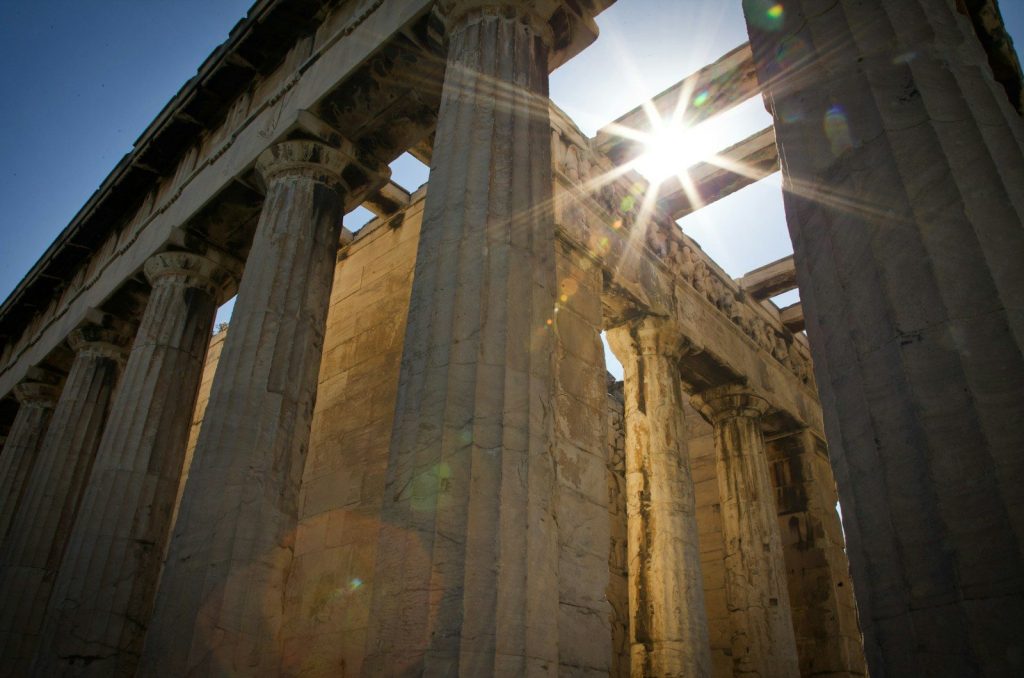 the sun shines brightly through the columns of a building