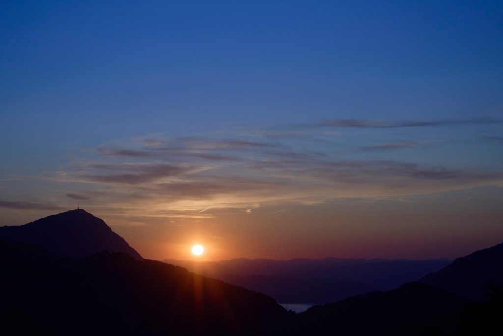 Sunrise over a mountain range with dark silhouettes.