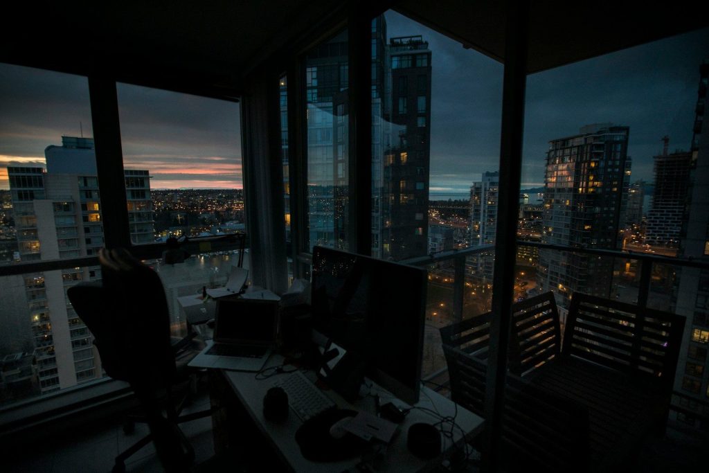 a desk with a computer on top of it in front of a window