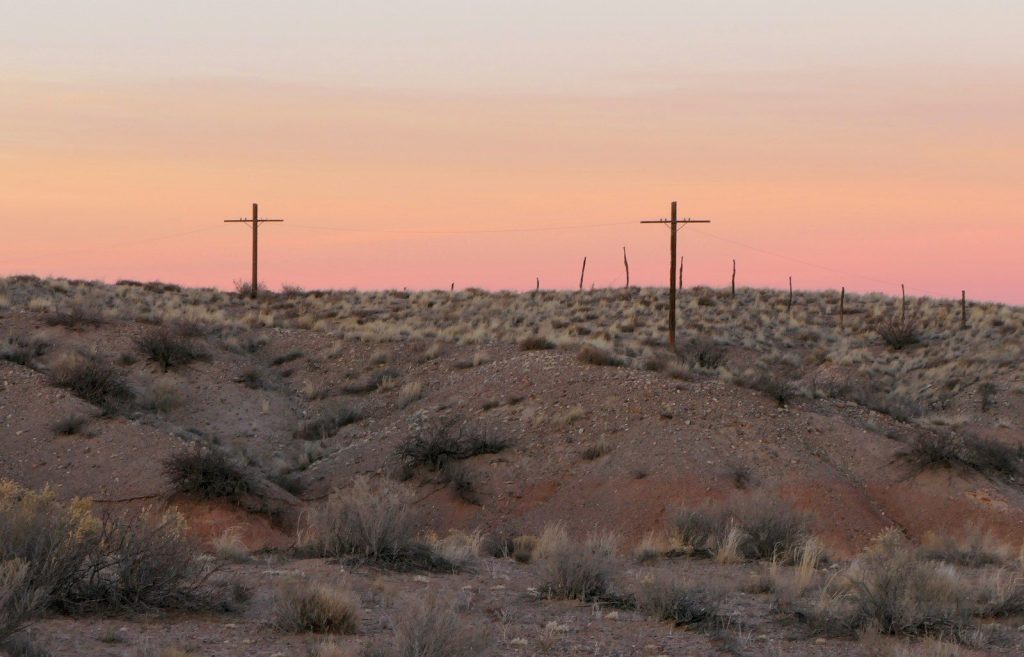 a desert landscape with two telephone poles in the distance