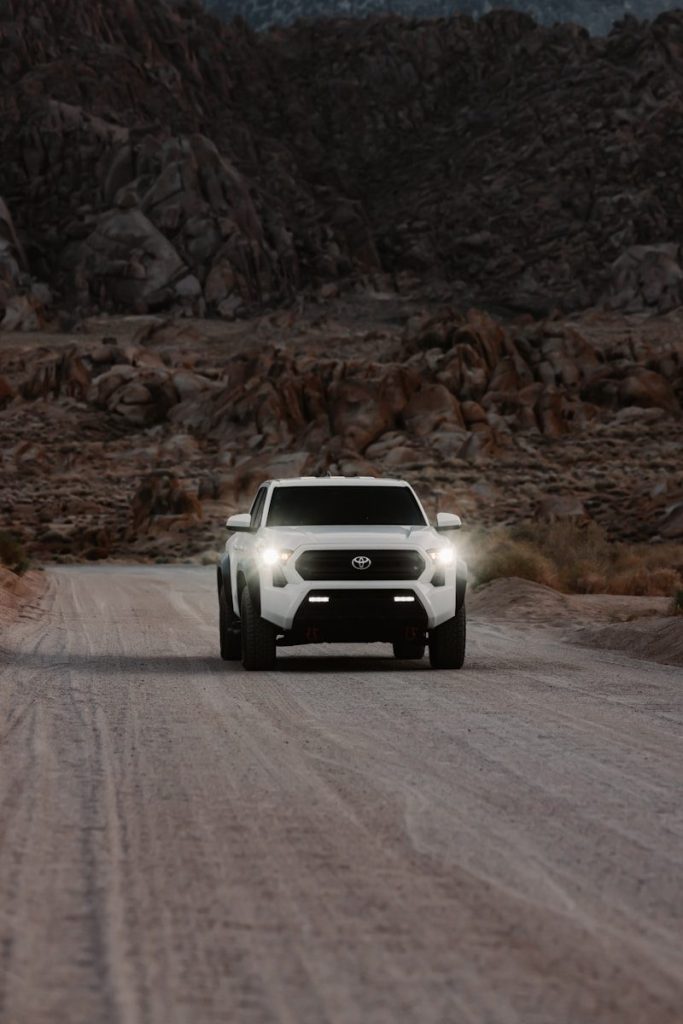 White truck driving on a dirt road.