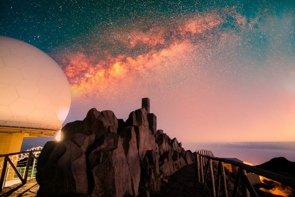 a large white ball sitting on top of a mountain under a sky filled with stars