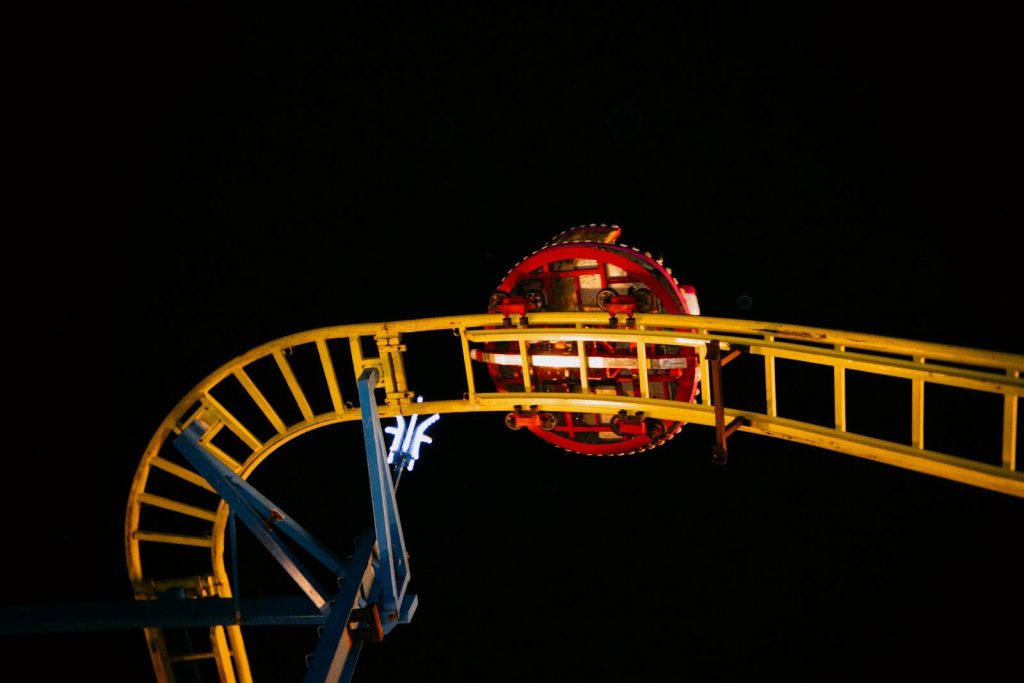 Roller coaster car ascends a track at night.