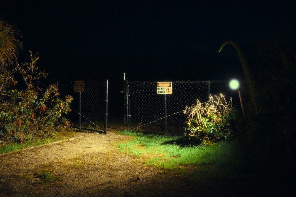 Chain-link fence gate at night with light