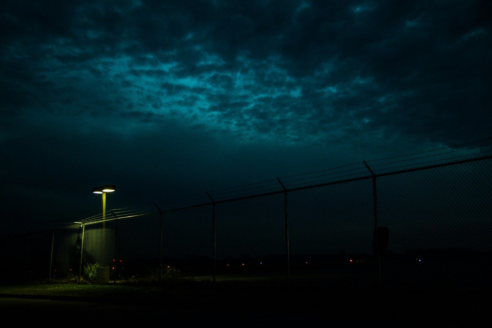 silhouette of light post under dark clouds