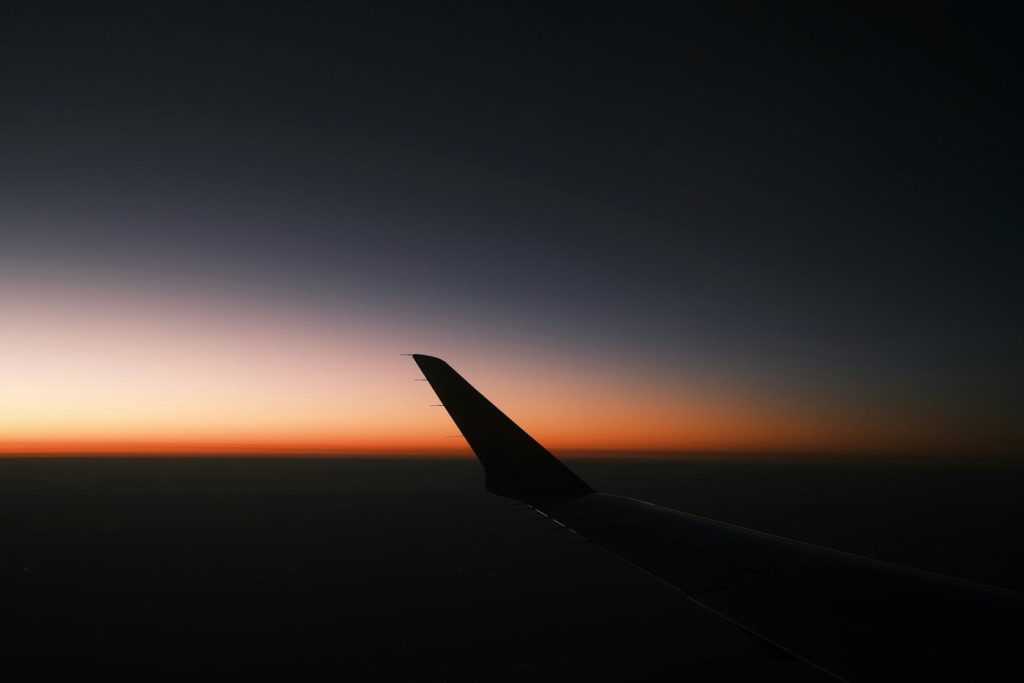 Airplane wing against a dark sky at sunset
