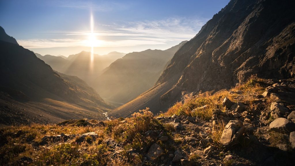 the sun shines brightly over a valley in the mountains
