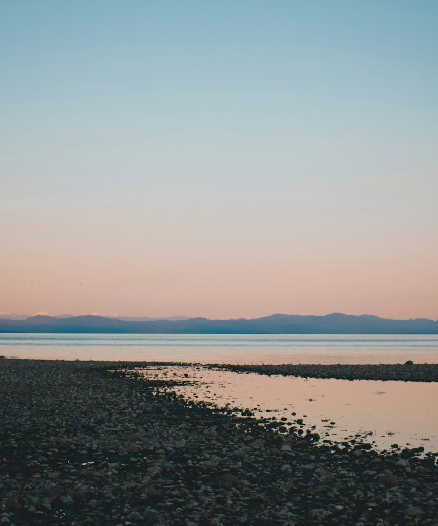 a beach with a body of water and mountains in the background