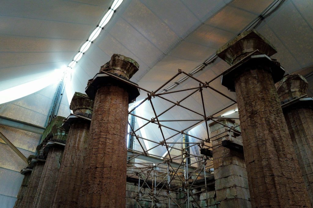 Ancient pillars are seen beneath a protective covering.