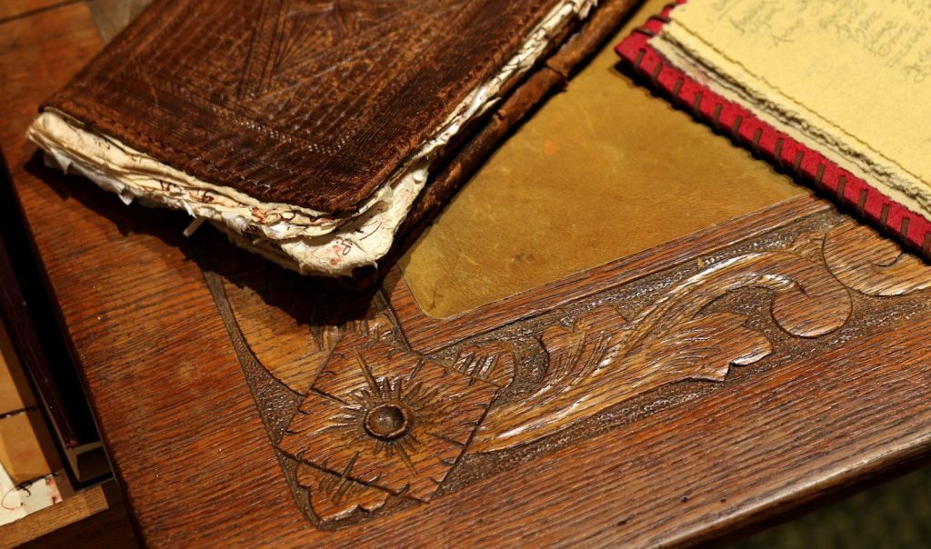Antique wooden desk with carved details and old books.
