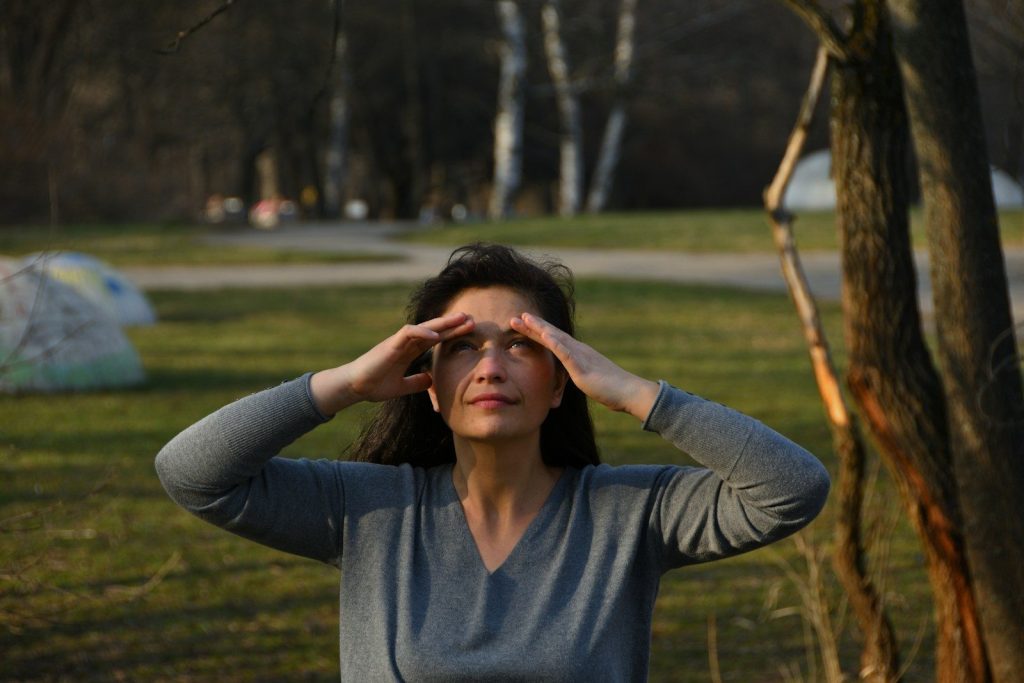 woman in blue v neck long sleeve shirt covering her face with her hands