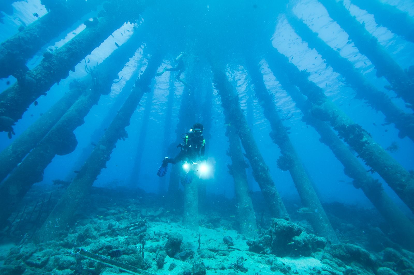 A scuba diver explores submerged structures in the clear waters of Bonaire.