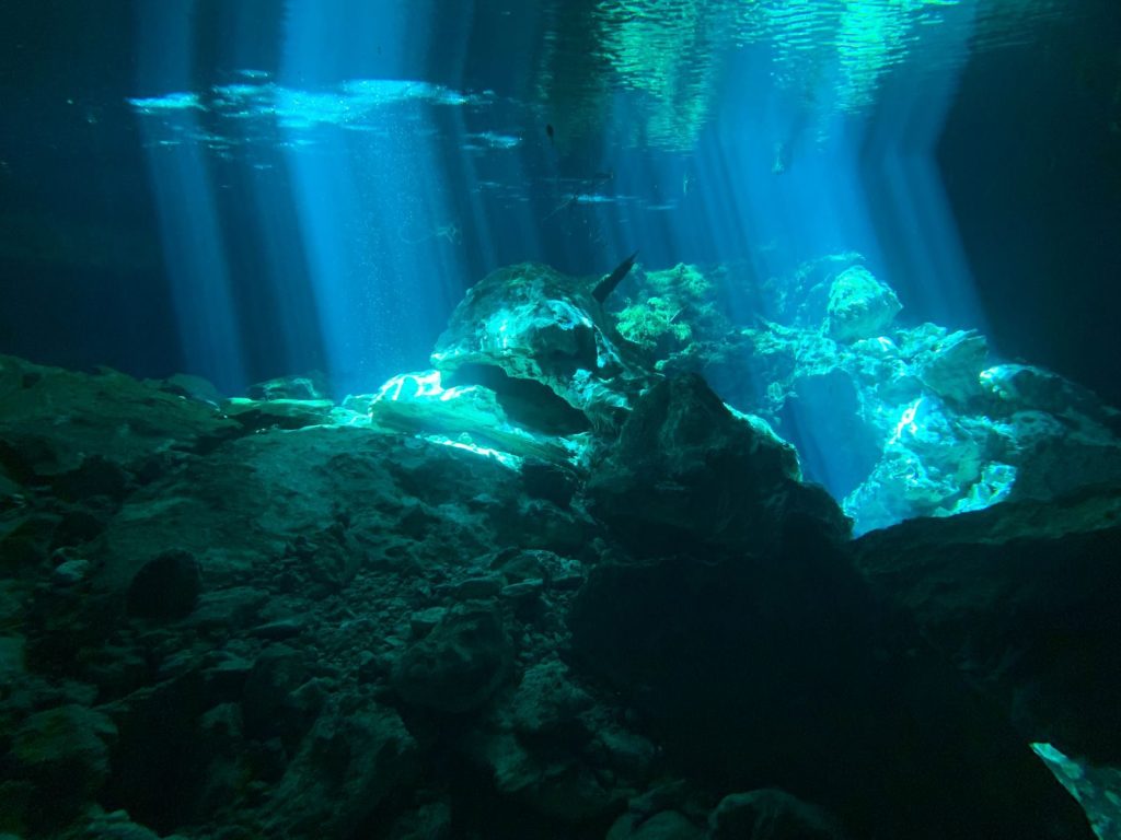 Beautiful underwater cave with dramatic sun rays illuminating the rocks.