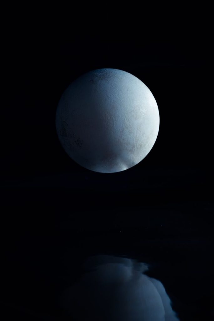 A mesmerizing view of a full moon reflecting on still water against a cosmic black background.
