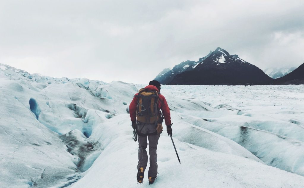 A lone adventurer hikes across a snowy glacier in Patagonia, Chile, during winter.