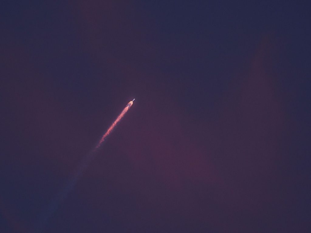 A stunning view of a rocket leaving a fiery trail as it ascends into the night sky.