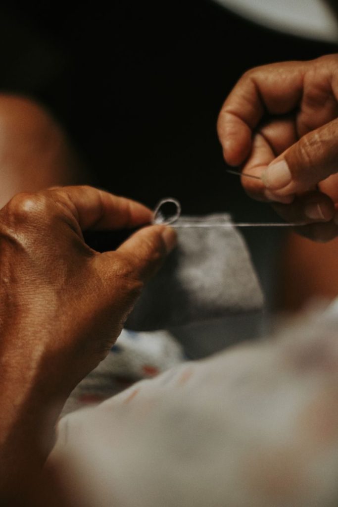 Detailed view of hands engaged in precise sewing work with a needle and thread.