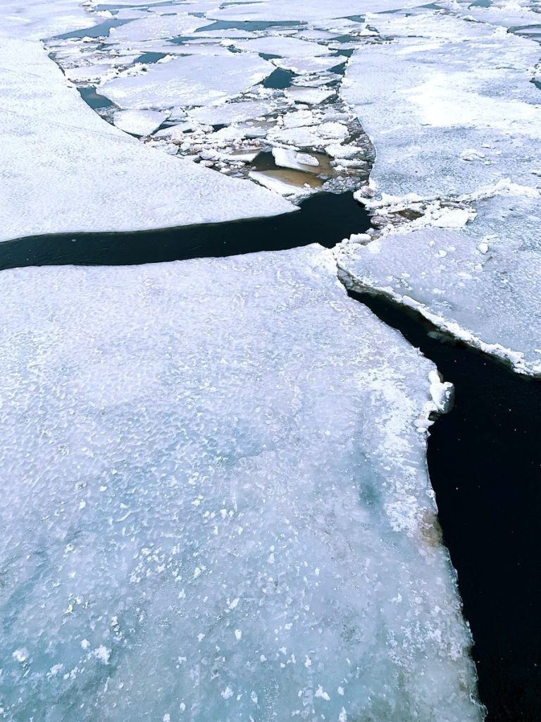 Aerial view of cracked frozen ice on a body of water during winter.