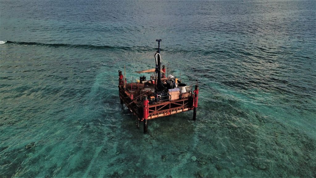 Aerial high-angle shot of an offshore platform in the clear waters of the Maldives.