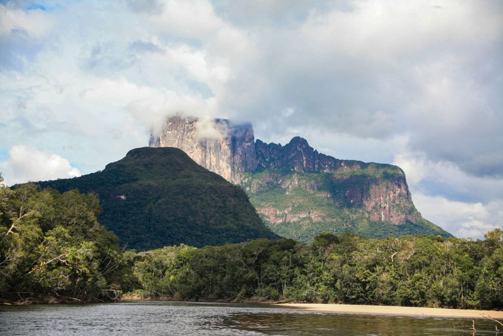 Scenic view of Cerro Autana surrounded by lush forest under a partly cloudy sky in Venezuela.