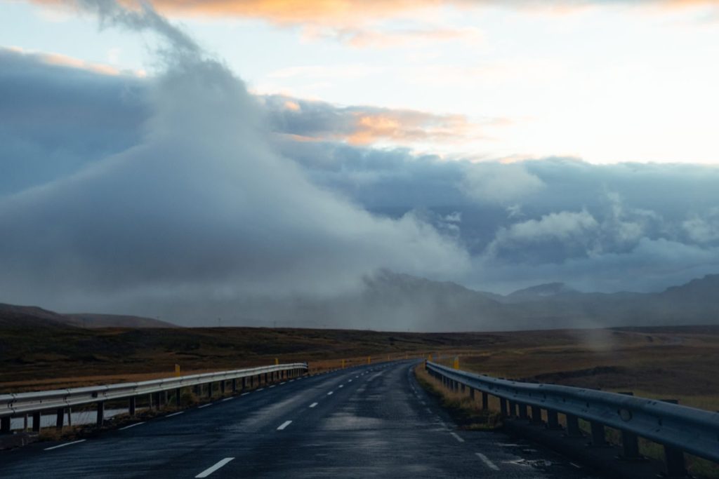 A scenic road under dramatic clouds in a vast landscape, perfect for travel themes.