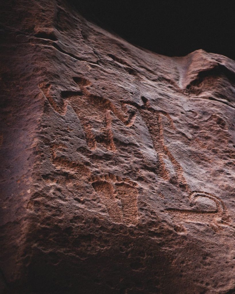 Close-up of prehistoric petroglyphs etched into sandstone, showcasing ancient art and history.