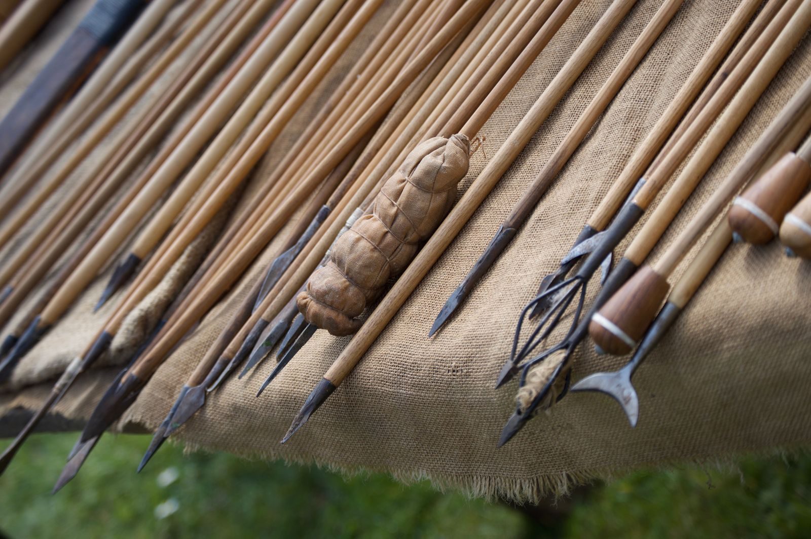 Close-up of traditional wooden javelins with distinct points laid on burlap fabric.