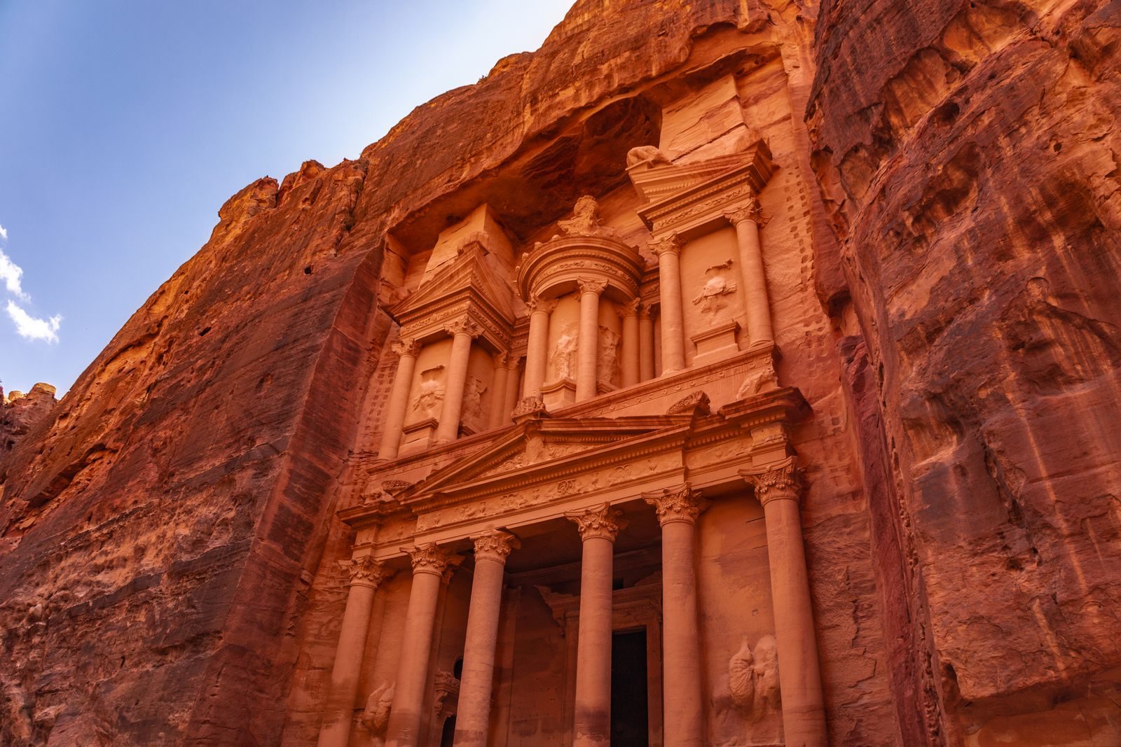 Explore the iconic Treasury at Petra, Jordan, bathed in warm, golden light against the rock cliffs.