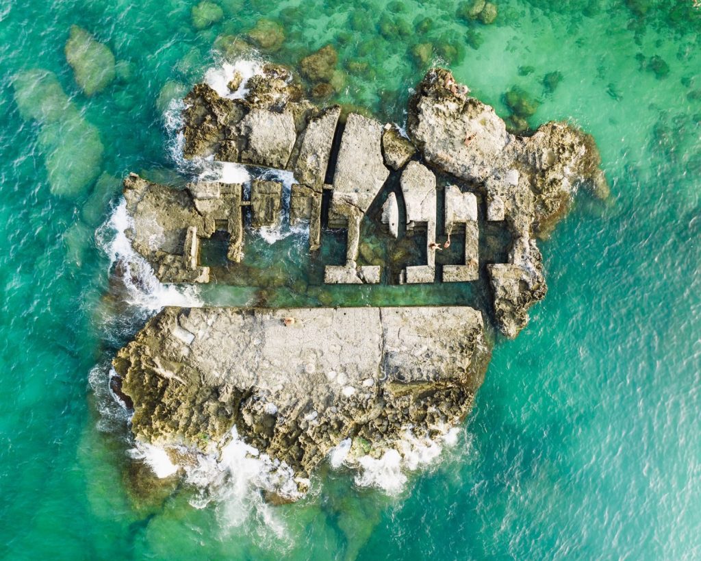 Aerial shot of a rocky island surrounded by turquoise water in Monopoli, Italy.