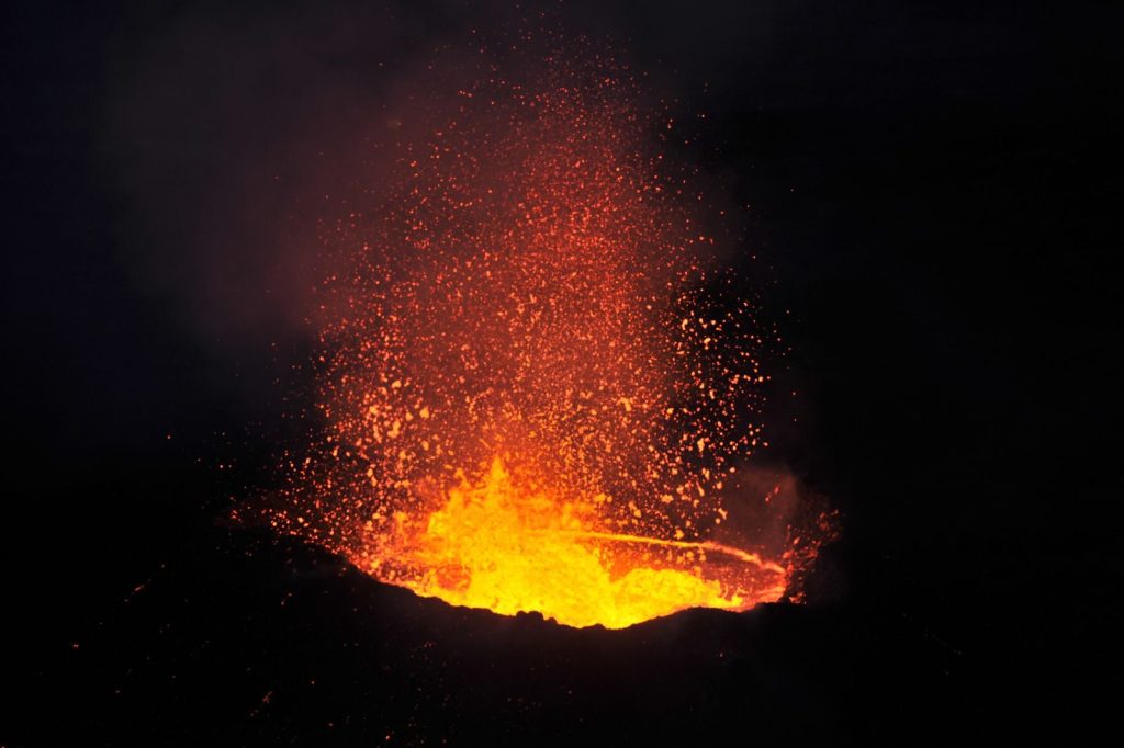 Stunning image of a volcano eruption with fiery lava against the night sky.