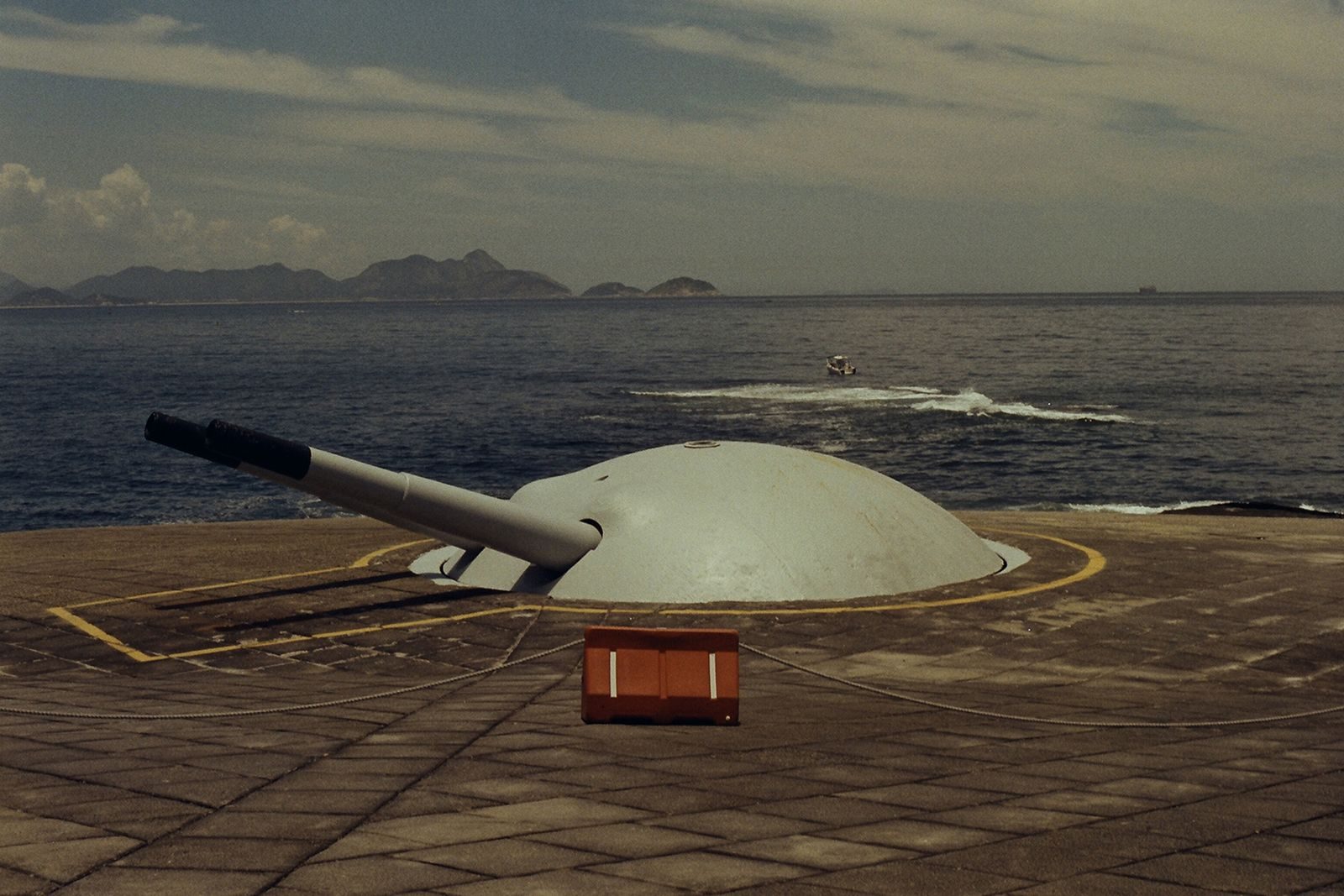 Vintage coastal defense cannon overlooking the ocean with distant islands visible.
