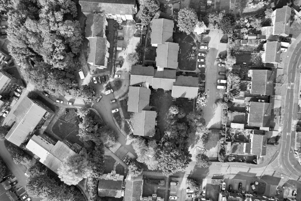 Drone shot showcasing rooftops, trees, and streets in a Luton neighborhood, England.