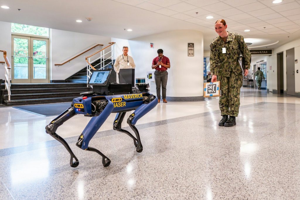 Robot dog and man in uniform in hallway