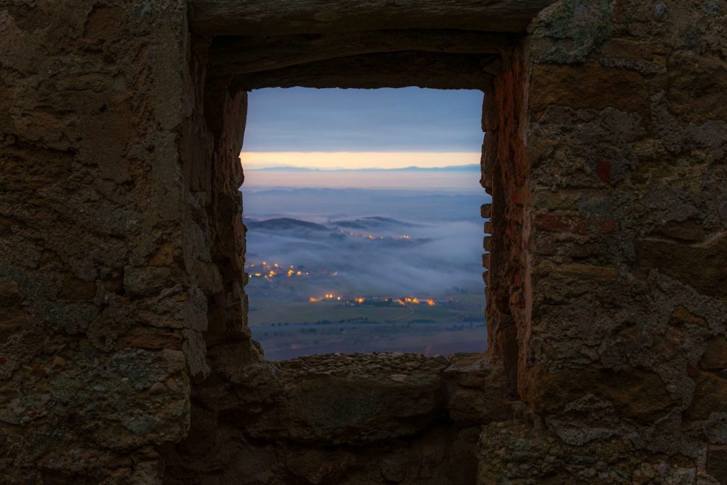 View of a misty valley with distant lights at dawn.