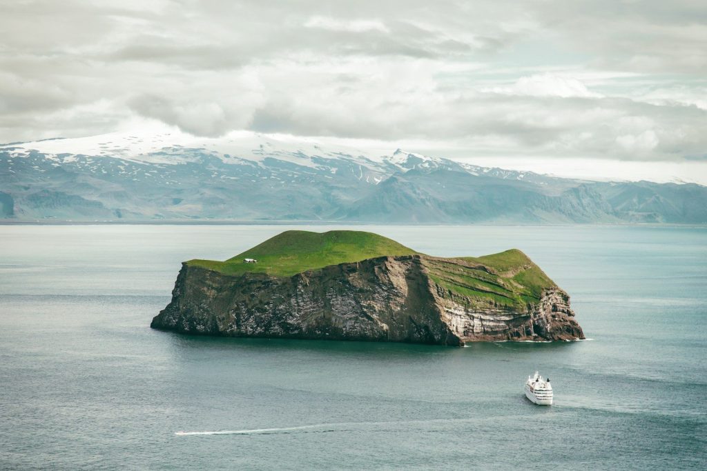 white boat on body of water near green and gray island