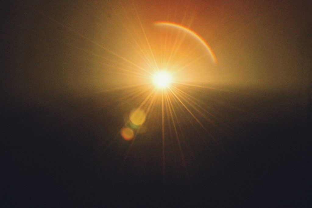 Bright sun with lens flare over dark horizon