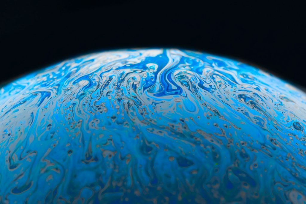 A mystical abstract image resembling a swirling blue planet with fluid textures.