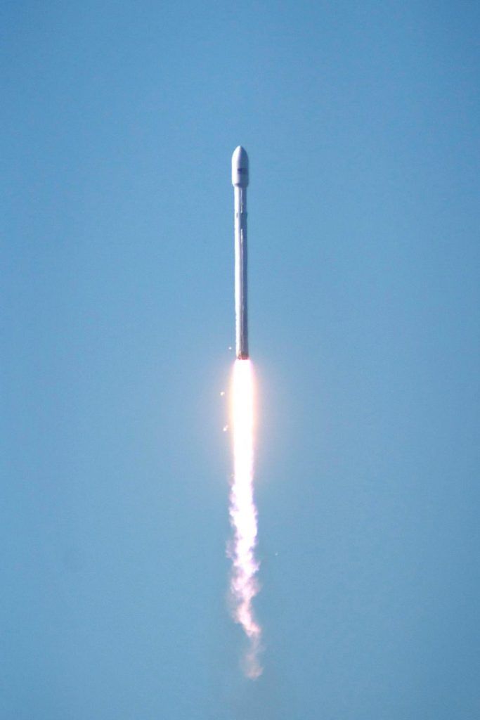 Falcon 9 rocket launching into space, showcasing powerful propulsion against a clear blue sky.