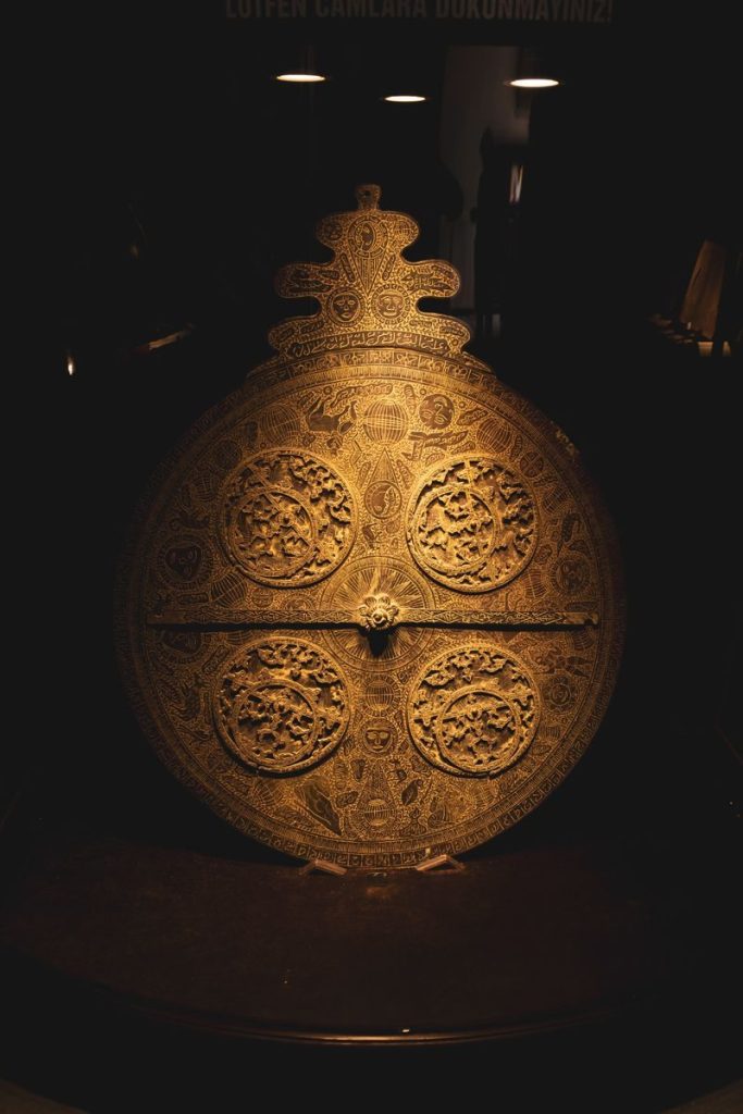 A detailed view of an ornately carved bronze shield displayed in a Konya museum.