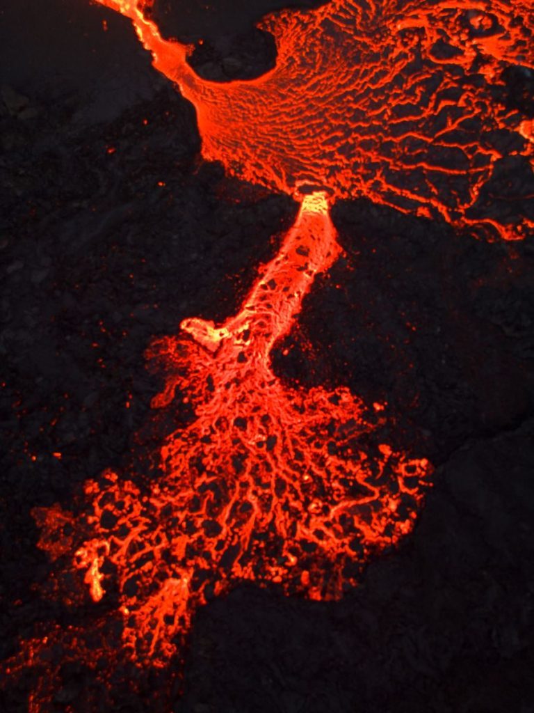 Close-up of vibrant molten lava flow with intricate textures in an Icelandic volcanic landscape.