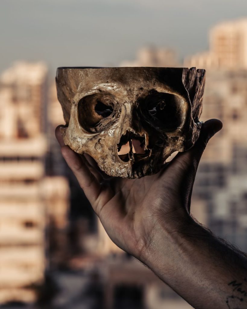 A creative portrait of a human skull held against a Buenos Aires cityscape background.