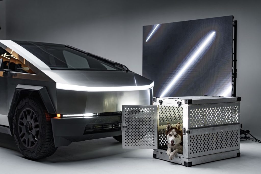 A sleek Cybertruck beside a Siberian Husky in a durable crate, indoors.