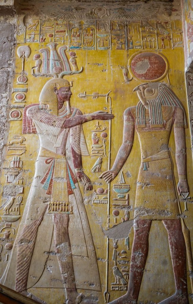 Intricate Egyptian hieroglyphs depicting deities on temple wall. Vibrant, historical art.