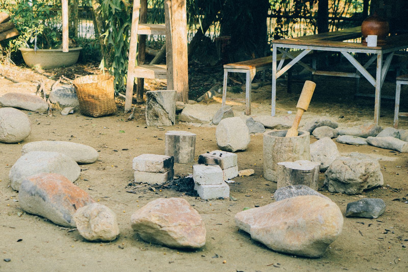 A charming outdoor setting featuring a rustic fire pit encircled by rocks and wooden seating, perfect for a cozy gathering.
