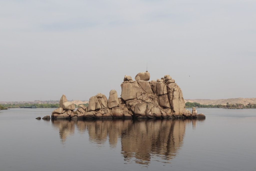 Scenic view of unique rock formations in Aswan, Egypt, reflected in calm waters.