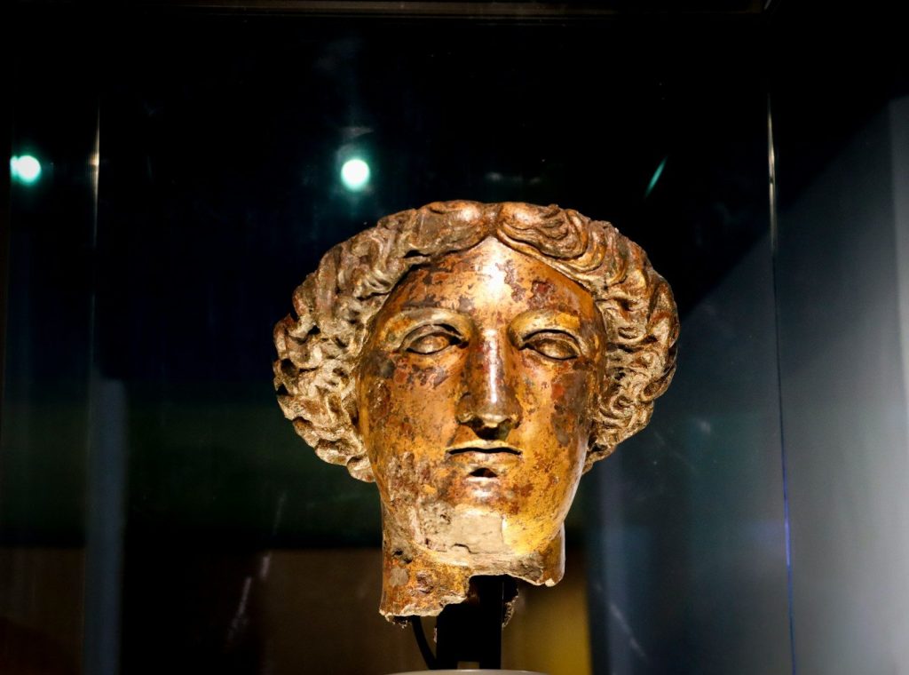 Ancient bronze bust of a woman with curly hair.