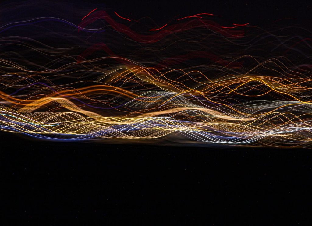 Intricate abstract light trails weave across a dark canvas, creating a mesmerizing visual effect.