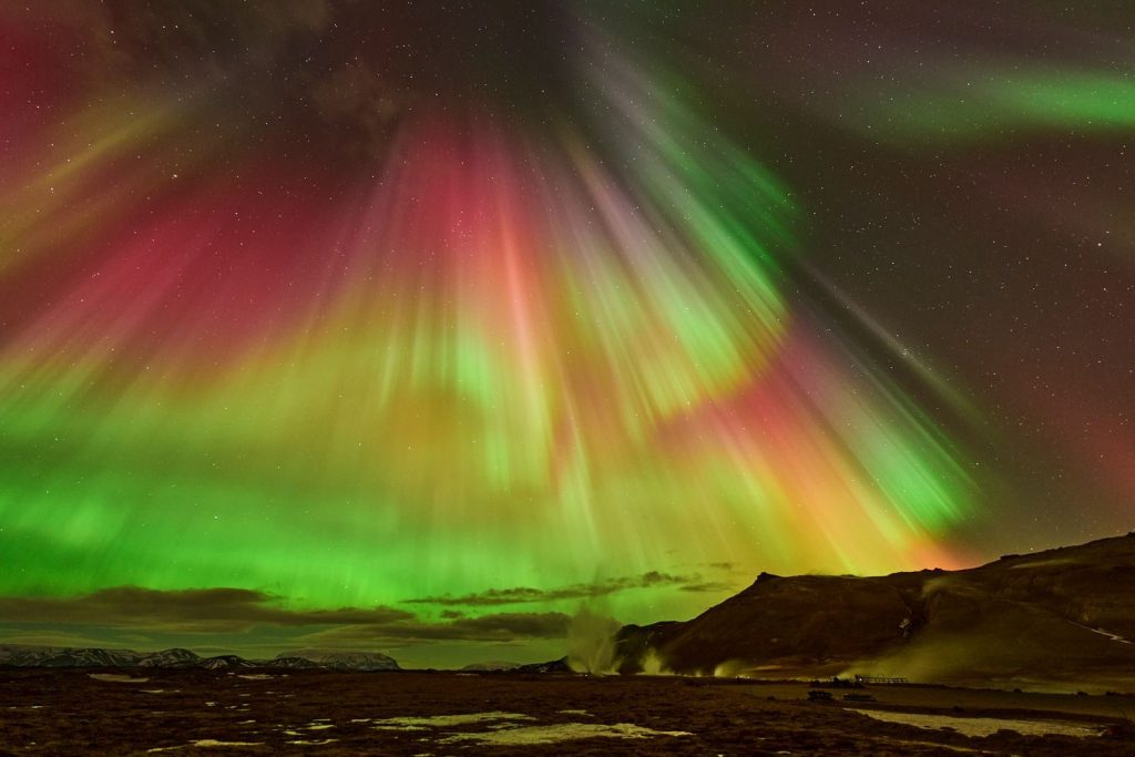 Breathtaking display of Northern Lights over Reykjahlíð, Iceland, with vibrant colors and starry night sky.