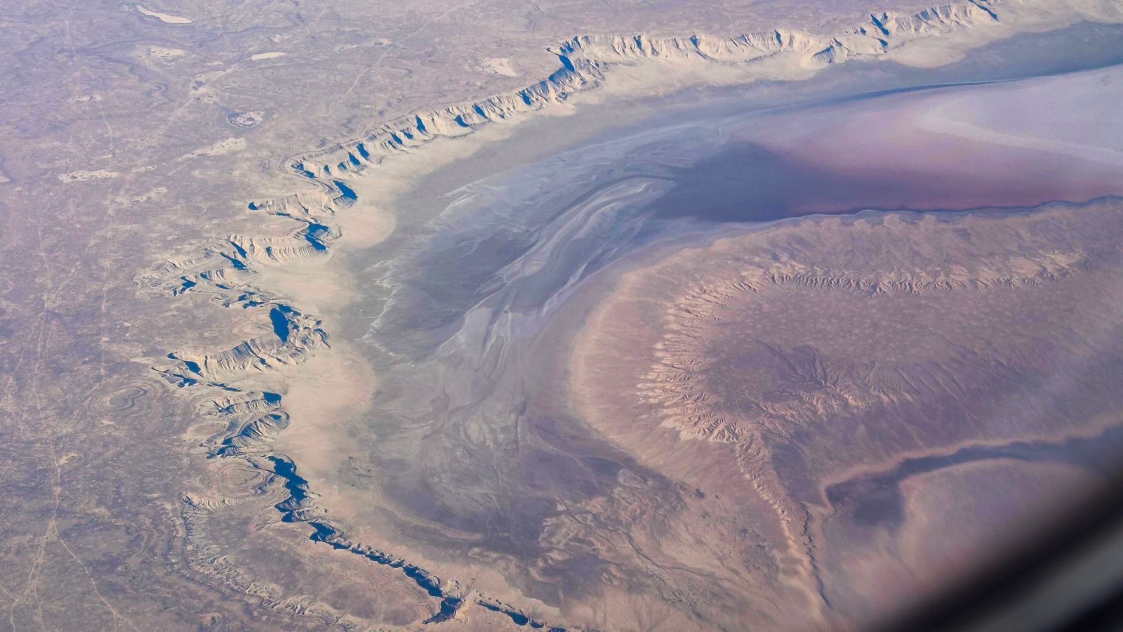 Aerial view of a rugged and barren desert with distinctive geological formations and erosion patterns.